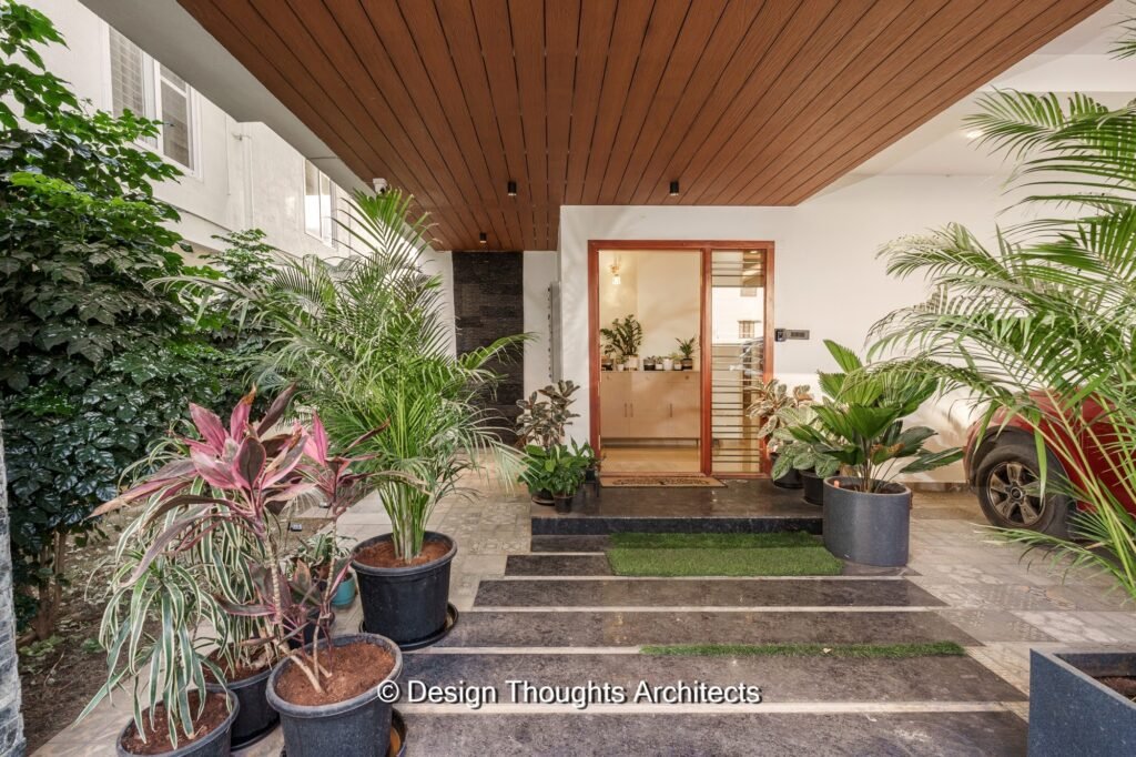 The entrance lobby with lush green landscaping creates a welcoming atmosphere in the east-facing plot home.