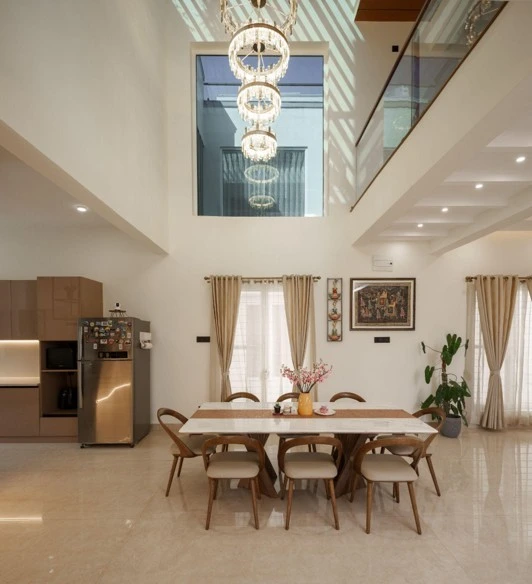 Modern interior showing double height dining area with chandelier and natural light